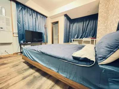 a bedroom with a bed with blue curtains and a television at \u95e8\u524d\u4ef2\u753a2\u5206\u949f 2\u6761\u5730\u94c1\u4ea4\u6c47 \u76f4\u901a\u4e1c\u4eac\u4e1c\u897f\u5357\u5317 \u623f\u95f4\u5bbd\u655e401 in Tokyo