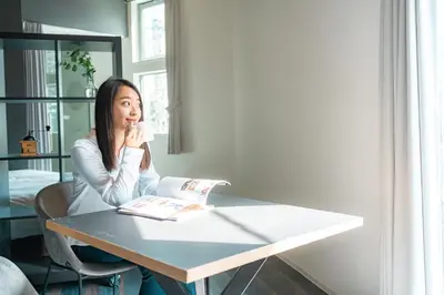 a woman sitting at a table reading a book at Corent\u4ee3\u7530\u6a4b in Tokyo