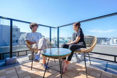 a man and a woman sitting in chairs on a balcony at unito KEIKYU-KAMATA in Tokyo