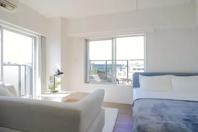 a white room with a bed and a couch and windows at unito KEIKYU-KAMATA in Tokyo