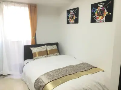 a bed in a bedroom with two pictures on the wall at 401 Oshiage sta 3mins walk! Wi-Fi Elevator 4pax in Tokyo