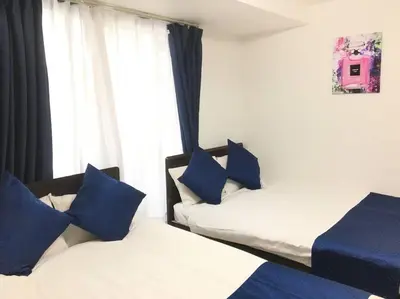 two beds with blue pillows in a room with a window at *301 Oshiage sta 3mins walk! Wi-Fi Elevator in Tokyo