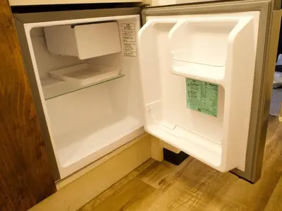 an empty refrigerator with its door open in a kitchen at The Hotel SPACE \u4e0b\u5317\u6ca2 in Tokyo