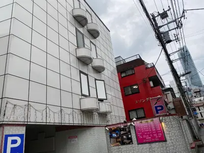 a tall white building with balconies and a red building at \u30db\u30c6\u30eb\u30d5\u30a9\u30fc\u30e9\u30e0 in Tokyo