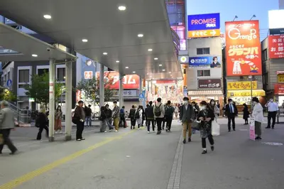 a group of people walking down a street in a city at \u30a2\u30f3\u30c9\u30b9\u30c6\u30a4\u4e2d\u91ce5\u4e01\u76ee203 in Tokyo