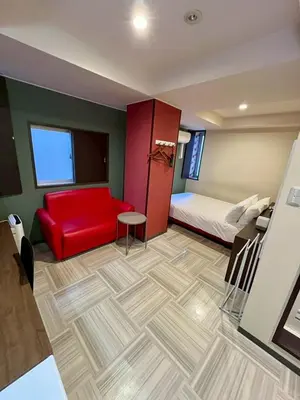 a room with a red couch and a bed at Hotel RIO\u65b0\u5bbf in Tokyo