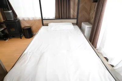 a bed in a small room with white sheets at AIC\u6c60\u888b502 in Tokyo