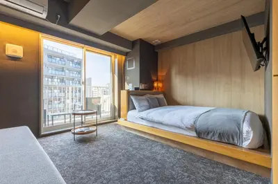 a bedroom with a bed and a large window at HOTEL TOMOS ASAKUSA in Tokyo