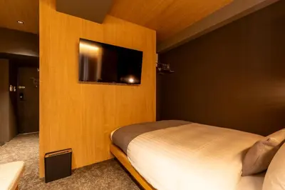 a bedroom with a bed and a flat screen tv at HOTEL TOMOS ASAKUSA in Tokyo