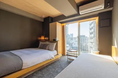 a bedroom with a bed and a large window at HOTEL TOMOS ASAKUSA in Tokyo