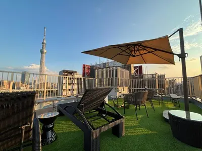 a patio with chairs and an umbrella and the eiffel tower at HOTEL TOMOS ASAKUSA in Tokyo