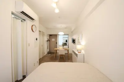 a white bedroom with a bed and a table at Vermidor Ebisu302 in Tokyo