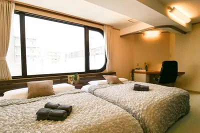 two beds in a room with a large window at KODAKA Hotel TOKYO in Tokyo