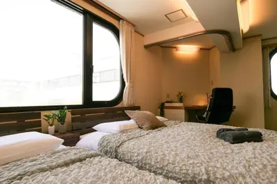two beds in a room with two windows at KODAKA Hotel TOKYO in Tokyo