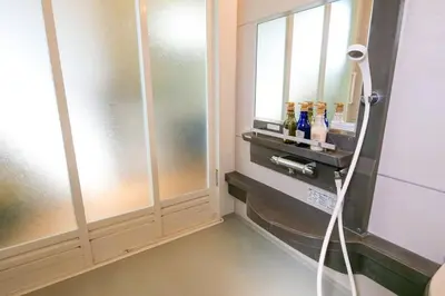 a bathroom with a shower with a sink and a mirror at KODAKA Hotel TOKYO in Tokyo