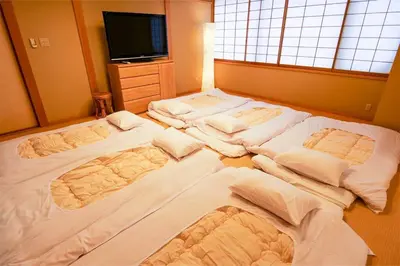a room with three beds in front of a tv at KODAKA Hotel TOKYO in Tokyo