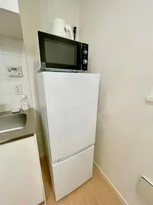 a microwave sitting on top of a refrigerator at SALON\u6e0b\u8c374B in Tokyo