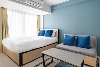 a bedroom with a bed and a couch with blue pillows at Sky Kinshicho in Tokyo
