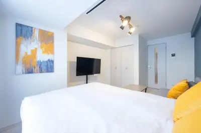 a bedroom with a white bed and a flat screen tv at Sky Kinshicho in Tokyo