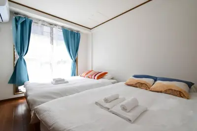 two beds in a room with blue curtains and a window at \u30e1\u30be\u30f3\u516b\u5343\u4ee3102 in Tokyo