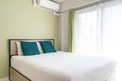 a bedroom with a bed with blue pillows and a window at \u30e9\u30a6\u30ec\u30a2\u30bf\u30ef\u30fc\u6c60\u888b in Tokyo