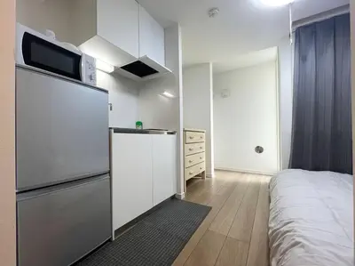 a kitchen with a refrigerator and a bed in a room at \u65b0\u5bbf\u30a8\u30ea\u30a2be\u30c6\u30e9\u30b9\u897f\u65b0\u5bbf in Tokyo