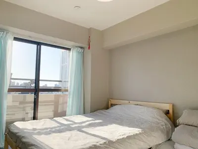 a bedroom with a bed and a large window at Shinjuku 2min walk! Shinjuku kabukicho \u6b4c\u821e\u4f0e\u753a! \u8f66\u7ad9\u6b65\u884c2\u5206! 2\u4e2a\u5367\u5ba4\u516c\u5bd3! \u65b0\u88c5\u4fee\u516c\u5bd3!\u5e72\u6e7f\u5206\u79bb! \u667a\u80fd\u9a6c\u6876! \u9ad8\u901f\u65e0\u9650\u5236\u7f51\u8def1001 in Tokyo