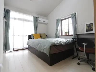 a bedroom with a bed and a desk and windows at \u6e21\u9089\u30d3\u30eb in Tokyo