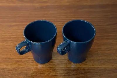 two blue cups sitting on top of a wooden table at \u5927\u4e95\u753a\u30a2\u30d1\u30fc\u30c8\u30e1\u30f3\u30c8\u30db\u30c6\u30eb\u8c4a\u5f37\u30d3\u30eb in Tokyo