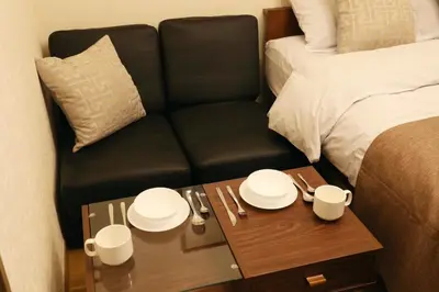 a room with a couch and a table with plates and mugs at \u5927\u4e95\u753a\u30a2\u30d1\u30fc\u30c8\u30e1\u30f3\u30c8\u30db\u30c6\u30eb\u8c4a\u5f37\u30d3\u30eb in Tokyo