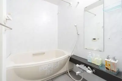 a white bathroom with a tub and a mirror at ANGO Shibuya I in Tokyo