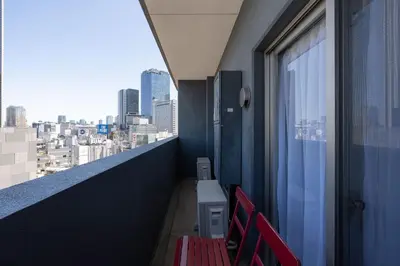 a balcony with red chairs and a view of a city at ANGO Shibuya I in Tokyo