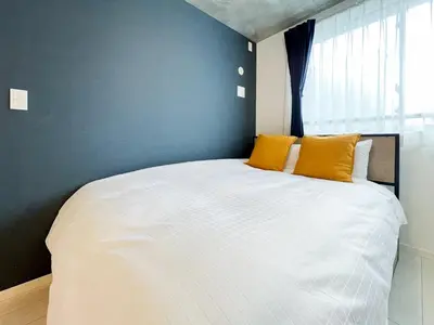 a bedroom with a large white bed with yellow pillows at \u30a6\u30a7\u30eb\u30b9\u30af\u30a8\u30a2\u30a4\u30ba\u30e0\u65b9\u5357\u753a in Tokyo
