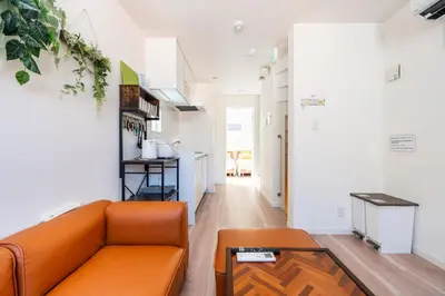 a living room with an orange couch and a table at \u30a2\u30f3\u30c9\u30b9\u30c6\u30a4\u4e0a\u9ad8\u75302\u4e01\u76ee in Tokyo
