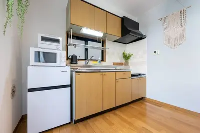 a kitchen with white appliances and wooden cabinets at Elle's Shirokane Guest house 301 in Tokyo