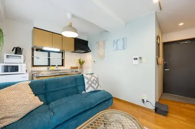 a living room with a blue couch and a kitchen at Elle's Shirokane Guest house 301 in Tokyo