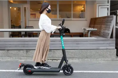 a woman wearing a mask riding a scooter at Elle's Shirokane Guest house 301 in Tokyo