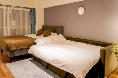 two beds in a room with a clock on the wall at New Design Apartment in Shinjuku Kabukicho! 3 mins station in Tokyo