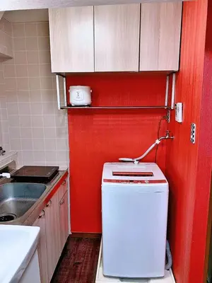 a small kitchen with red walls and a small refrigerator at Ueno\u4e0a\u91ce!Akihabara\u79cb\u8449\u539f!Asakusa \u6d45\u8349!3min walk to station!\u4ea4\u901a\u4fbf\u5229\u5730\u70b9\u7e41\u534e!\u9644\u8fd1\u7f8e\u98df!\u5546\u573a\u767e\u8d27\u904d\u5730! \u5e72\u6e7f\u5206\u79bb! \u667a\u80fd\u9a6c\u6876! \u9ad8\u901f\u65e0\u9650\u5236\u7f51\u8def! \u9ad8\u7ea7\u516c\u5bd3403 in Tokyo