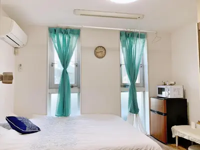 a bedroom with a bed with blue curtains and a clock at Shinjuku \u65b0\u5bbf\u5f92\u6b65\u5708!\u897f\u65b0\u5bbf!\u90fd\u5385!\u65b0\u5bbf\u4e2d\u592e\u516c\u56ed!2\u5206\u949f\u6b65\u884c\u5230\u5730\u94c1!\u9ad8\u901f\u65e0\u9650\u5236\u7f51\u7edc!\u7cbe\u81f4\u516c\u5bd3Autolock!104 in Tokyo