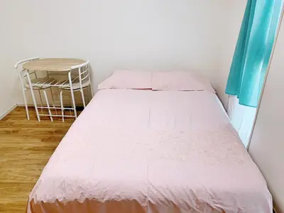 a bed with pink sheets and a chair in a room at Shinjuku \u65b0\u5bbf\u5f92\u6b65\u5708!\u897f\u65b0\u5bbf!\u90fd\u5385!\u65b0\u5bbf\u4e2d\u592e\u516c\u56ed!2\u5206\u949f\u6b65\u884c\u5230\u5730\u94c1!\u9ad8\u901f\u65e0\u9650\u5236\u7f51\u7edc!\u7cbe\u81f4\u516c\u5bd3Autolock!104 in Tokyo