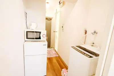 a small kitchen with a microwave on top of a refrigerator at Near Shinjuku!Nishi Shinjuku Gochome 6min!\u897f\u65b0\u5bbf!\u5730\u94c1\u7ad9\u6b65\u884c6\u5206!\u65b0\u5bbf\u5f92\u6b65\u5708!\u7cbe\u81f4\u516c\u5bd3! \u9ad8\u901f\u65e0\u9650\u5236WIFI 203 in Tokyo