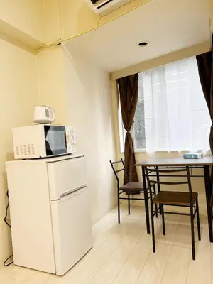 a kitchen with a white refrigerator and a table with a microwave at Ikebukuro Center# Ikebukuro 5min walk#\u6c60\u888b\u4e2d\u5fc3\u5730\u5e26# \u6c60\u888b\u8f66\u7ad9\u6b65\u884c5\u5206#\u65e0\u9650\u5236wifi #\u6771\u5efa702 in Tokyo