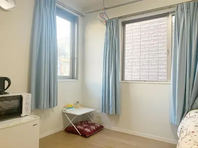 a bedroom with blue curtains and a bed and a television at \u9ad8\u7530\u99ac\u5834 T akadababa subway, 5-Minute Walk from New room BC in Tokyo