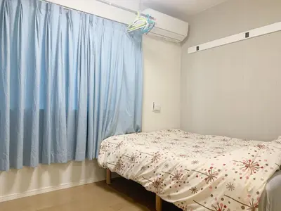 a bedroom with a bed and a blue curtain at \u9ad8\u7530\u99ac\u5834 T akadababa subway, 5-Minute Walk from New room BC in Tokyo