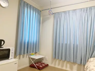 a bedroom with blue curtains and a television at \u9ad8\u7530\u99ac\u5834 T akadababa subway, 5-Minute Walk from New room BC in Tokyo