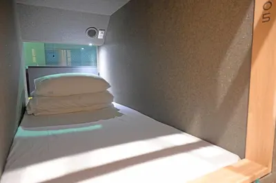 a small bed in a small room with a window at ELE Cabin Shinjuku Kabukicho in Tokyo