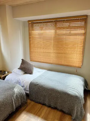 a bedroom with two beds and a window with blinds at Akihabara K in Tokyo
