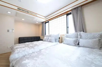 a bedroom with two beds and a large window at la3 hotel \u65b0\u5bbf\u4e09\u968e\u5efa\u3066\u4e00\u8ed2\u5bb6\uff08\u5c4b\u5185\u30a8\u30ec\u30d9\u30fc\u30bf\u30fc\u4ed8\u304d) in Tokyo