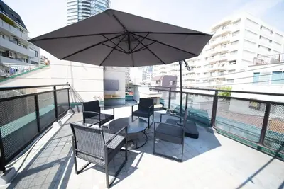 a balcony with a table and chairs and an umbrella at la3 hotel \u65b0\u5bbf\u4e09\u968e\u5efa\u3066\u4e00\u8ed2\u5bb6\uff08\u5c4b\u5185\u30a8\u30ec\u30d9\u30fc\u30bf\u30fc\u4ed8\u304d) in Tokyo